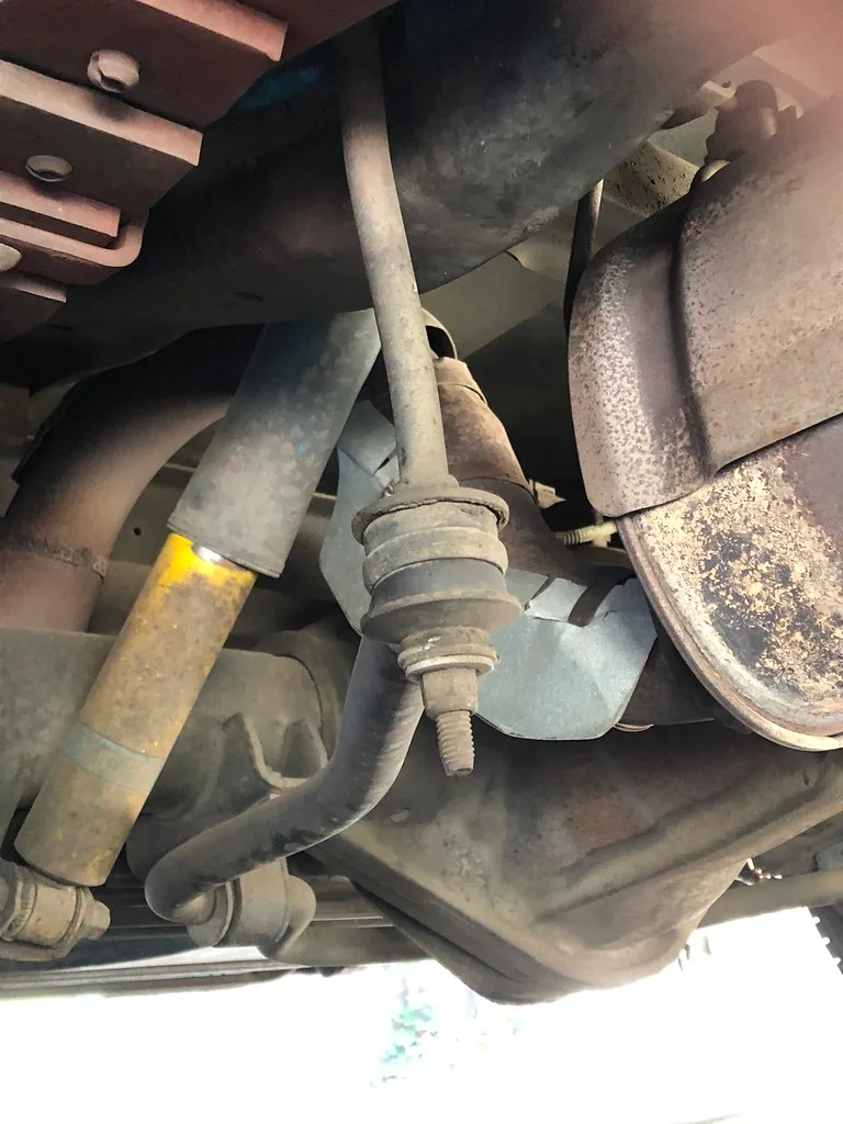 Mechanic inspecting front suspension and sway bar links on a lifted car
