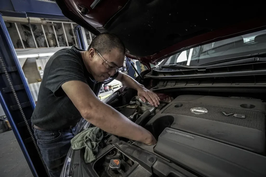Car maintenance before a long road trip with a driver and mechanic inspecting an open hood