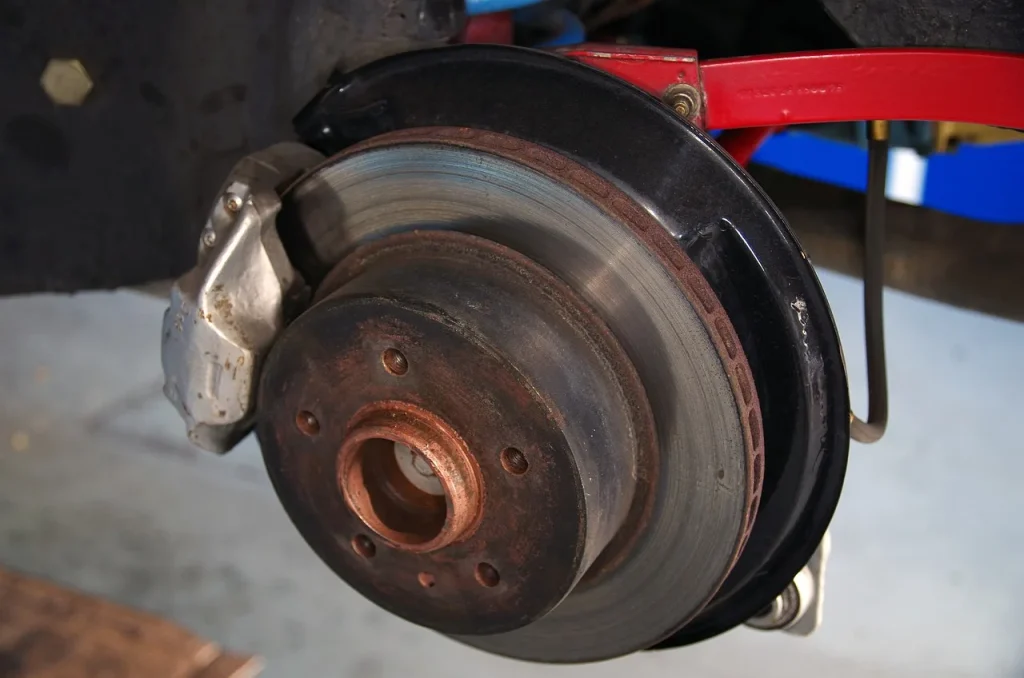 Mechanic inspecting a car brake rotor and caliper in a repair bay
