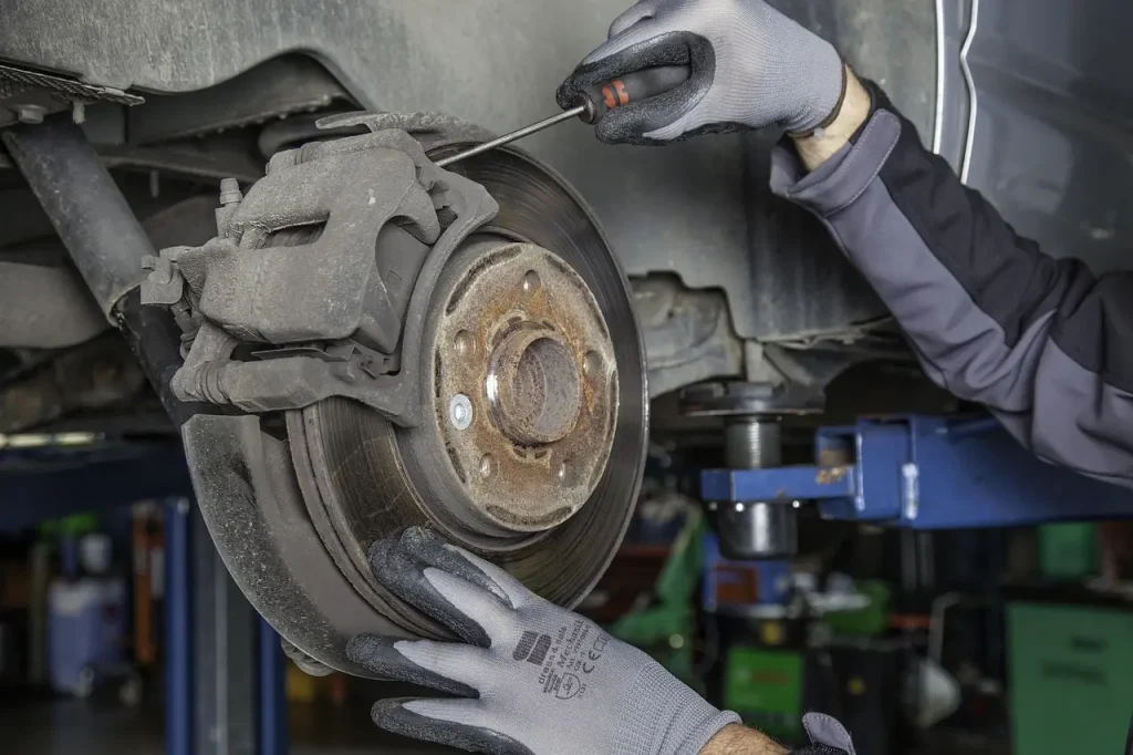 Mechanic comparing ceramic and metallic brake pads beside a car in a sunlit garage