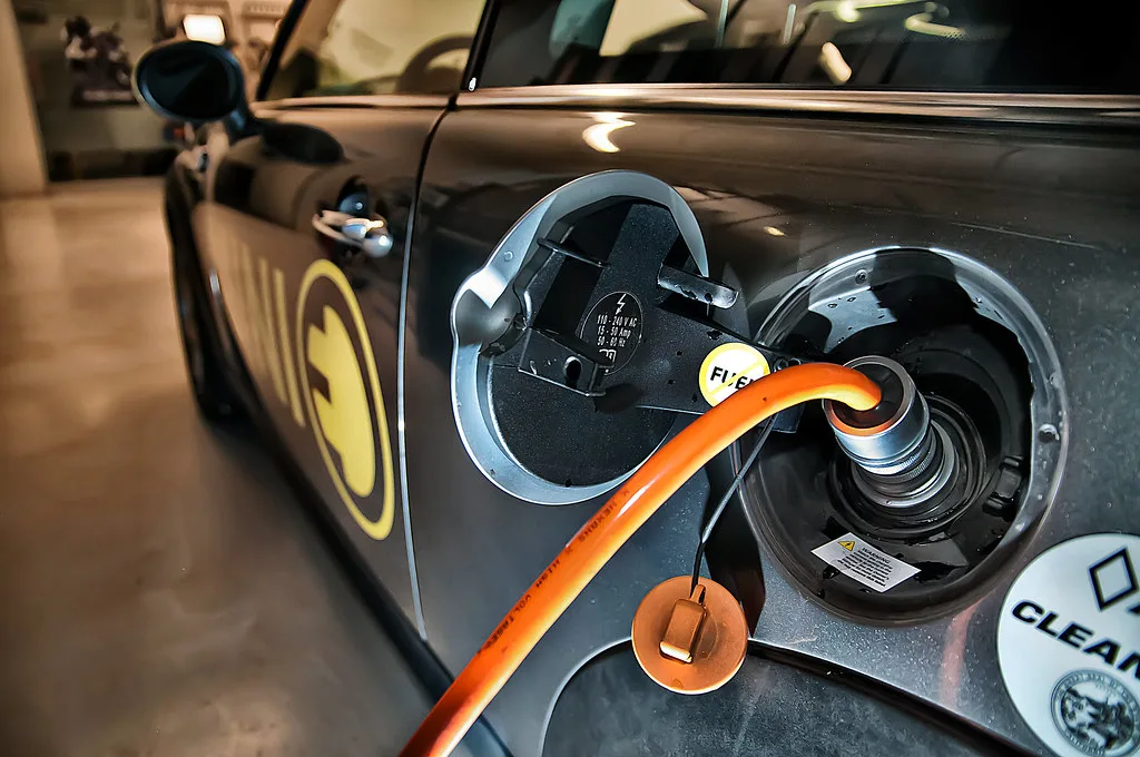 Multimeter testing a car battery with clamp leads attached to the terminals