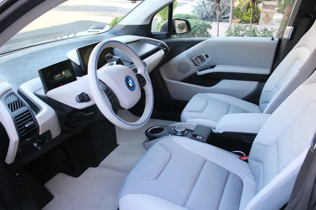 Car interior cleaning products arranged beside leather, fabric, vinyl, and a touchscreen in natural light
