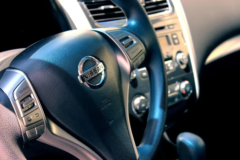 Person cleaning a car interior with a brush, microfiber cloth, and dustpan in natural daylight