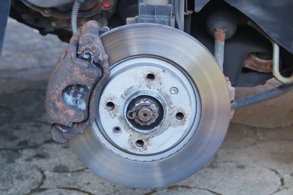 Mechanic inspecting a car's front wheel and brake components during a braking shimmy check