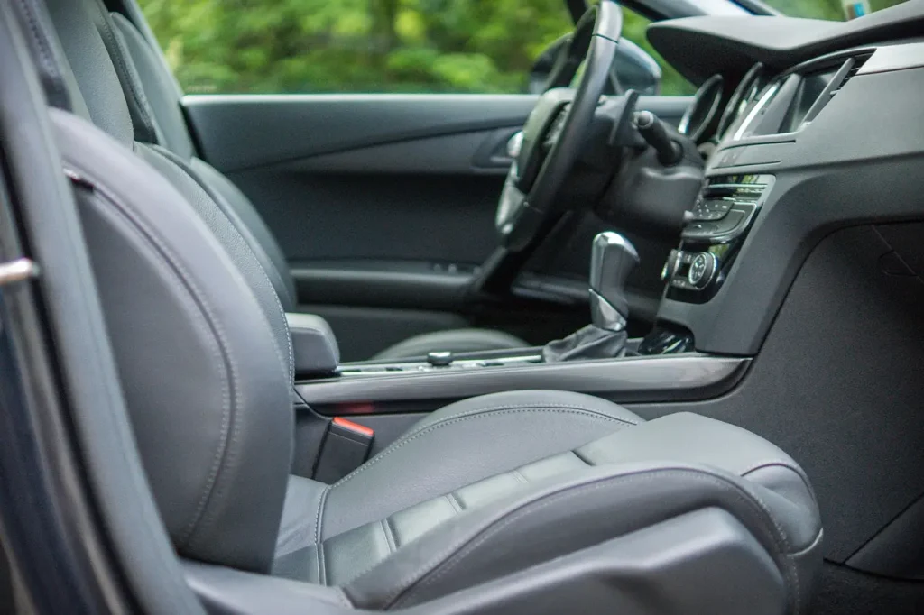 Faded car interior trim being inspected on a dashboard and door panel in natural light