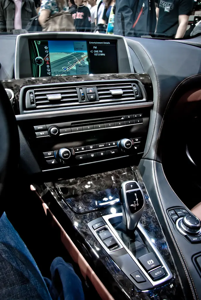 Hands cleaning a faded plastic car trim panel with a microfiber cloth