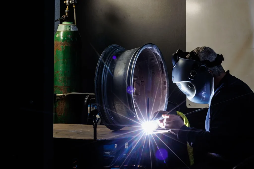 Mechanic inspecting the back of a wheel on a workbench with a flashlight and calipers