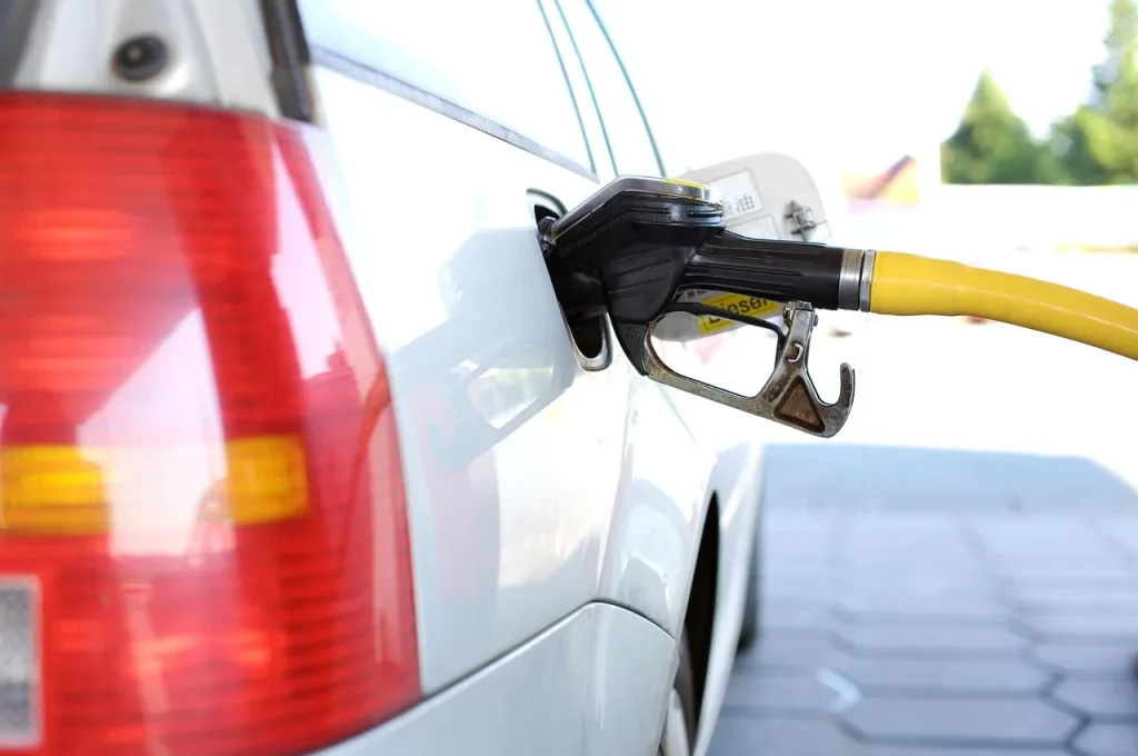Mechanic diagnosing a fuel pump on a sedan with the hood open at dusk