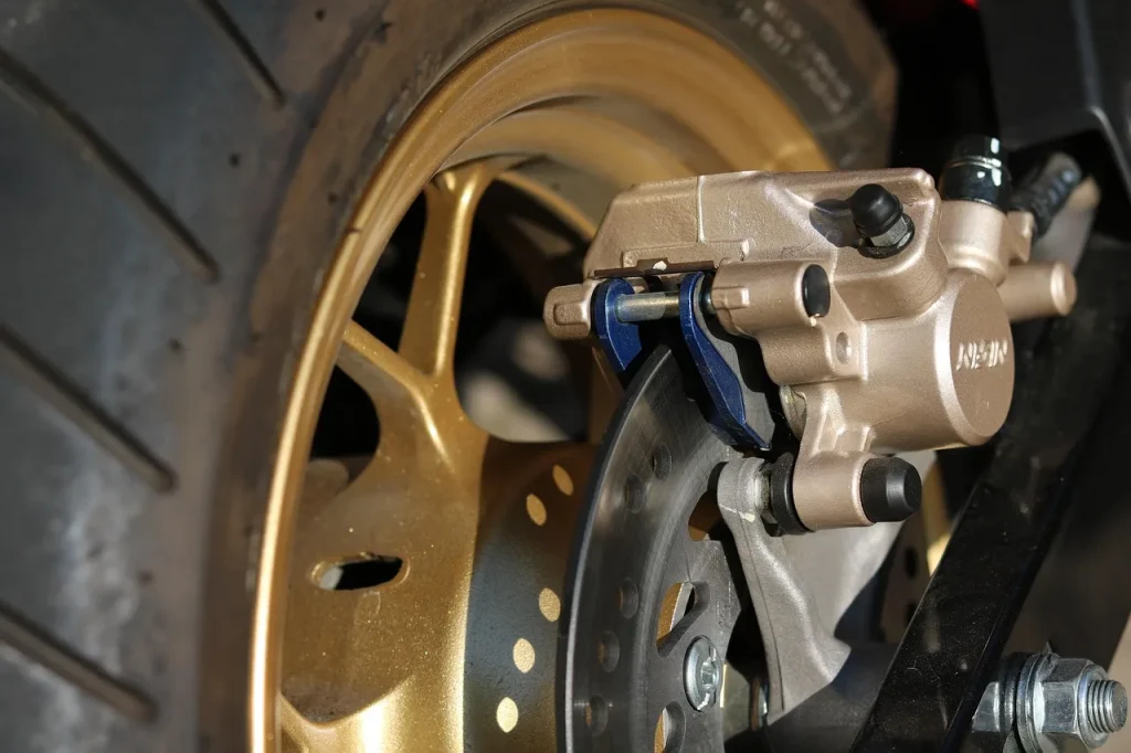 Mechanic inspecting a car brake rotor and caliper in a repair bay