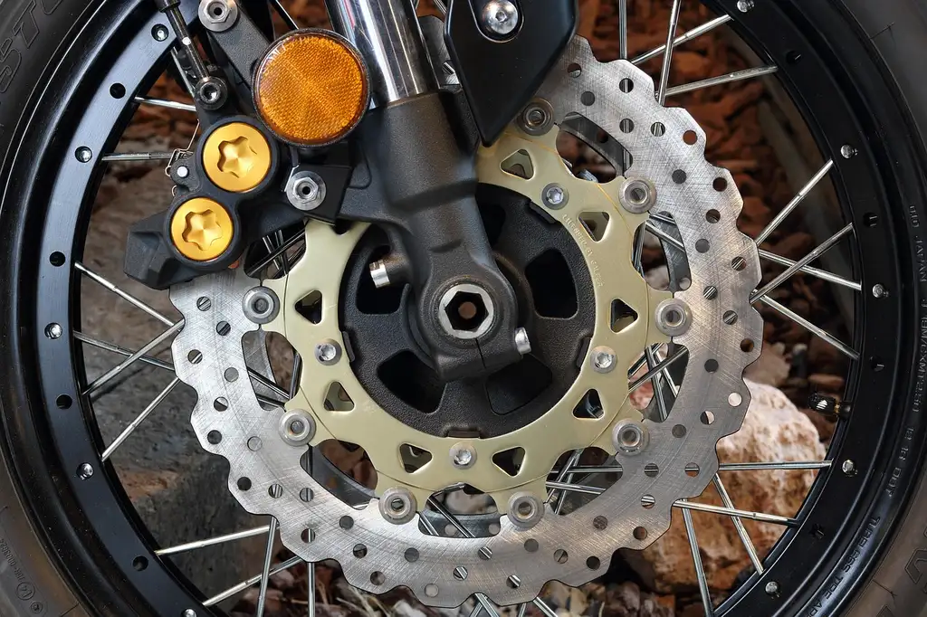 Mechanic inspecting the rear brake rotor and caliper on a sedan lift