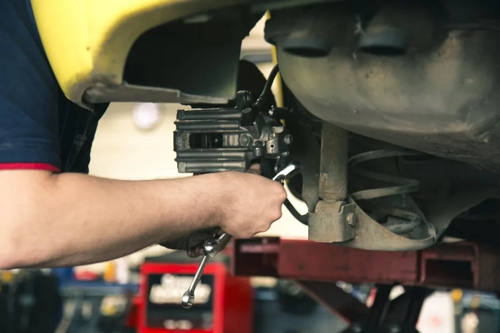 Mechanic and car owner reviewing a 50,000-mile checklist beside a sedan with the hood open