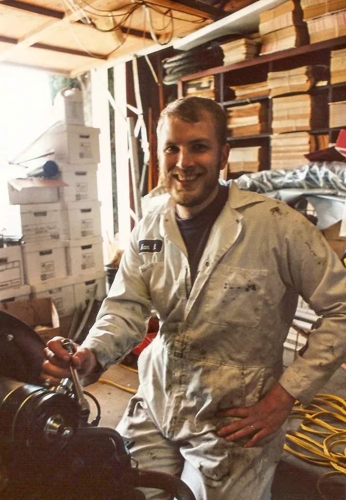 Mechanic checking a car battery with open caps and low electrolyte under the hood