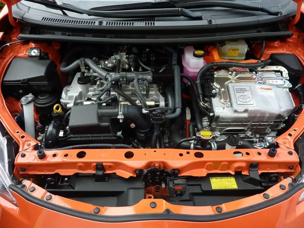 Car battery inspection with the hood open in a driveway on a sunny day